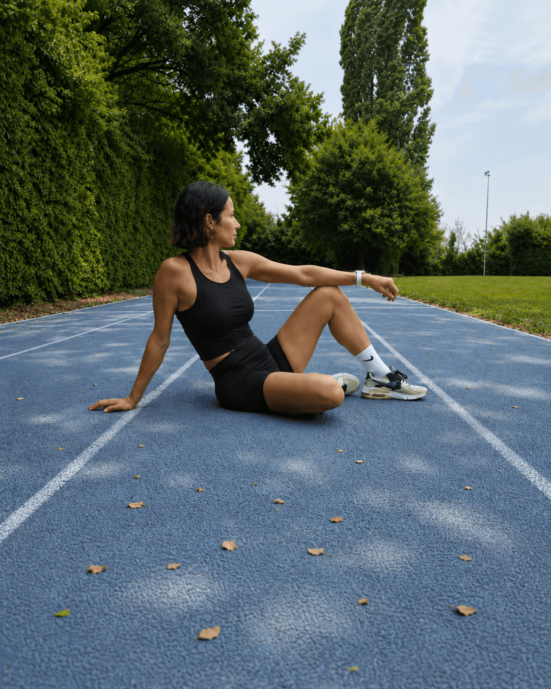 Katey taking an athletic break while seated on a light-blue running track